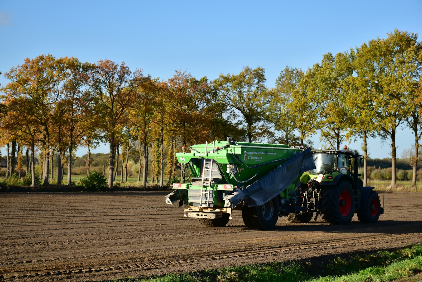 Photo by Ries Bosch a tractor is driving down a dirt road