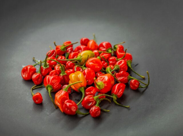a pile of red and yellow peppers on a black plate